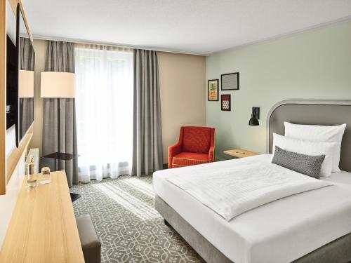 ein Hotelzimmer mit einem Bett und einem roten Stuhl in der Unterkunft MAXX Hotel Sanssouci Potsdam in Potsdam