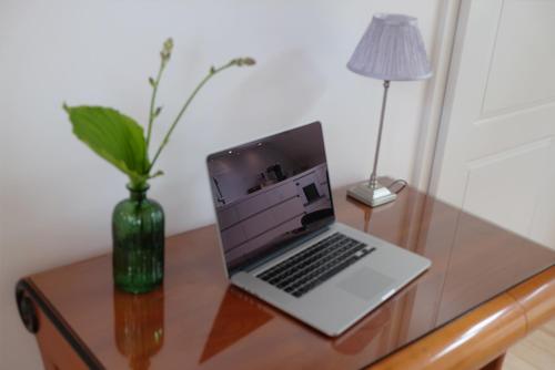 a laptop computer sitting on a wooden desk with a vase at Alte Apotheke - Studio Appartements Karlsbad in Karlsbad