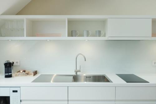 Alte Apotheke - Studio Appartements Karlsbad في كارلسباد: مطبخ أبيض مع حوض ودواليب بيضاء