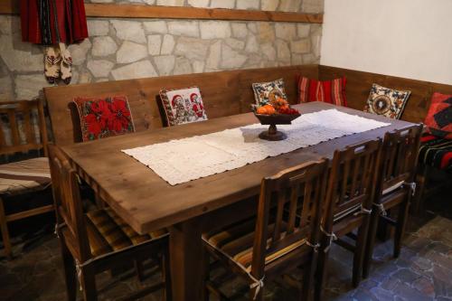 a wooden table with chairs and a bowl of fruit on it at Тодорината къща in Leshten