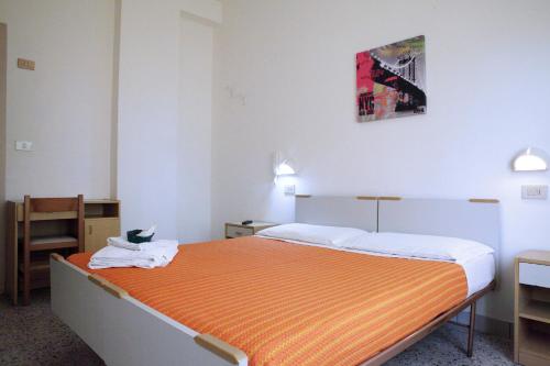 una camera d'albergo con un letto con una coperta arancione di Hotel Lagomaggio a Rimini