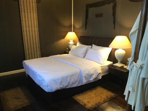 a bedroom with a bed with white sheets and two lamps at Mesilau Mountain Retreats in Kundasang