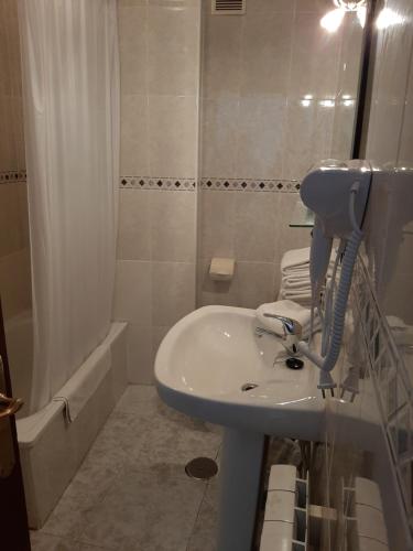 a white bathroom with a sink and a shower at Pensión Vista Alegre in Vigo