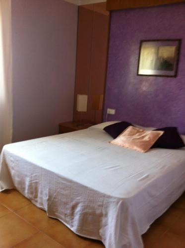 a bedroom with a large white bed with a purple wall at Can Quilis in Pontós