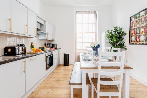 a kitchen with white cabinets and a table with chairs at Bright & Spacious 4beds home - Kensington High Street-Olympia in London