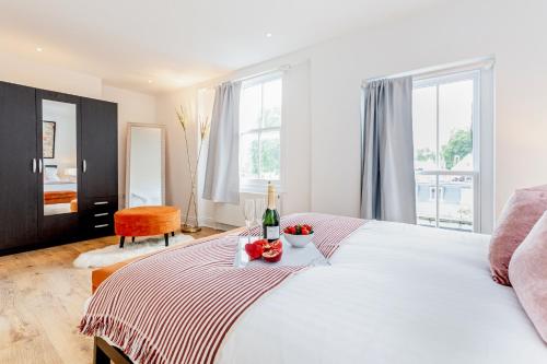 a bedroom with a bed with a bottle of wine and fruit on it at Bright & Spacious 4beds home - Kensington High Street-Olympia in London