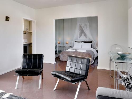 a bedroom with a bed and two black chairs at Carcavelos Beach&Bike House (view, parking, wi-fi) in Carcavelos