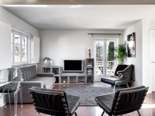 a living room with a couch and chairs and a tv at Carcavelos Beach&Bike House (view, parking, wi-fi) in Carcavelos
