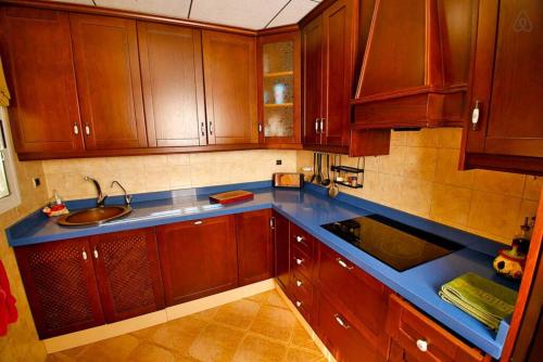 a kitchen with wooden cabinets and a blue counter top at Arenales Great Home with AC, Pool and Barbecue in Arenales del Sol