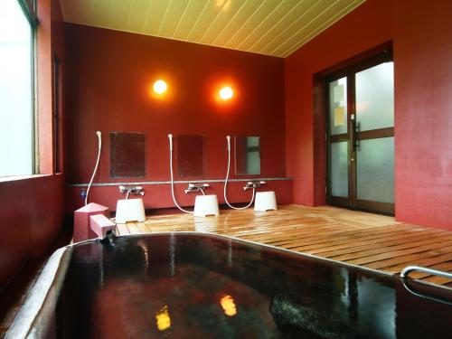 uma banheira num quarto com paredes vermelhas em Hotel Mumon em Myoko