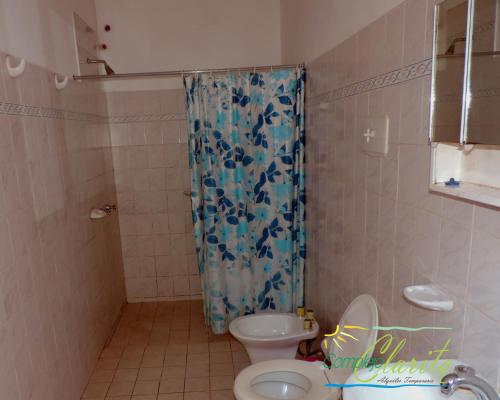 y baño con cortina de ducha y aseo. en Complejo Clarita en Villa Carlos Paz