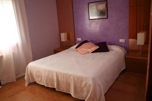 a bedroom with a white bed with purple walls at Can Quilis in Pontós