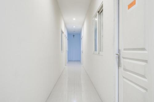 a hallway with white walls and an open door at RedDoorz at Siwalankerto Surabaya in Surabaya