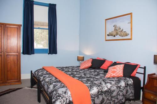 a bedroom with a bed with an orange blanket on it at Kimba Travellers' Haven in Kimba