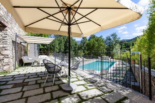 a patio with an umbrella and a swimming pool at Castello di Pontebosio Luxury Resort in Licciana Nardi