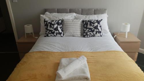 ein Bett mit zwei Kissen und Handtüchern darauf in der Unterkunft Gateshead's Amethyst 3 Bedroom Apt, Sleeps 6 Guests in Gateshead