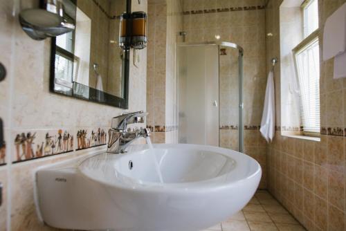 a white bath tub sitting next to a white sink at Villa Viktoriya Hotel in Truskavets