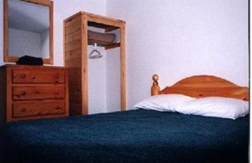 a bedroom with a bed and a dresser and a mirror at Chisholms of Troy Coastal Cottages in Port Hawkesbury