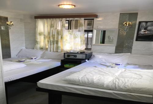 two beds in a hotel room with white sheets at Rich Hostel in Hong Kong