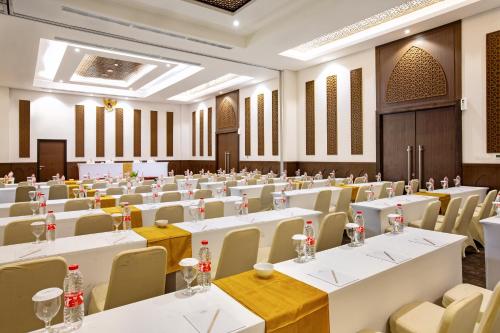 a banquet hall with white tables and chairs at Hotel Santika Gresik in Gresik