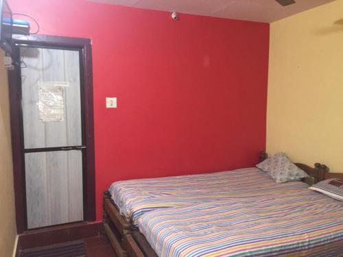 a bedroom with a bed with a red wall at Nimmu Guest House & Restaurant Gokarna in Gokarna