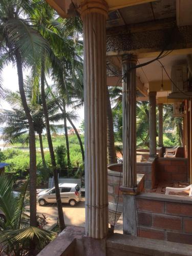 a house with columns and a car parked in a parking lot at Nimmu Guest House & Restaurant Gokarna in Gokarna