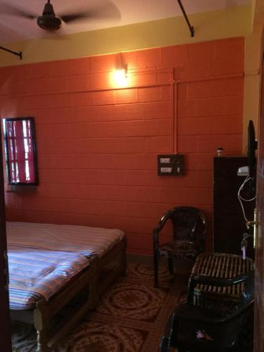 a room with a red wall with a bed and a chair at Nimmu Guest House & Restaurant Gokarna in Gokarna