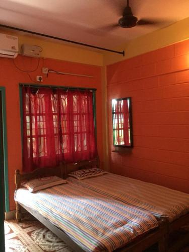 a bed in a room with red walls and windows at Nimmu Guest House & Restaurant Gokarna in Gokarna