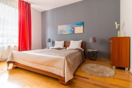 1 dormitorio con 1 cama grande y cortina roja en King Apartments, en Budapest