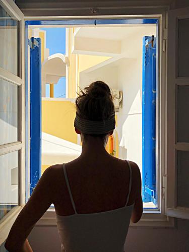 a woman is looking out of a window at Lefteris Traditional Rooms in Fira