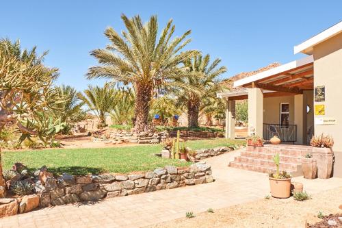 un patio trasero con palmeras y una pared de piedra en Apollis Cottage, en Springbok