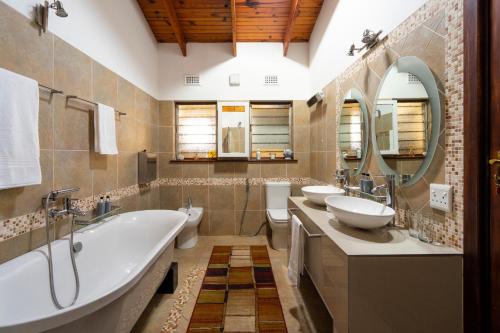 a bathroom with two sinks and a tub and mirrors at The Anchorage Krantzkloof in Kloof