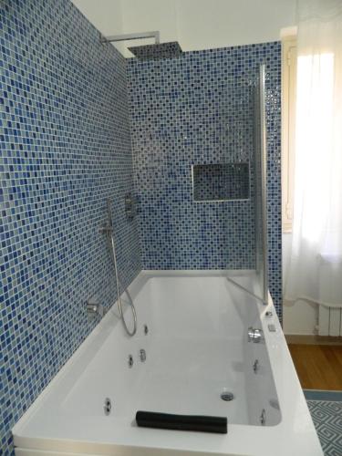 y baño con bañera blanca y azulejos azules. en LE STANZE DI LUCA, en Palermo