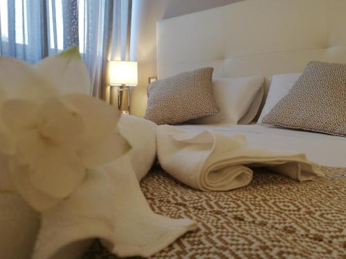 a bedroom with a white bed with a flower on the floor at Kaloneiro Guest House in Corigliano dʼOtranto