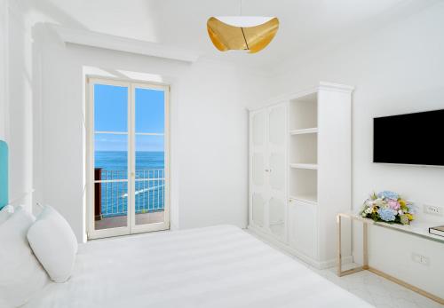 a white living room with a television and a window at Hotel Lorelei Londres in Sorrento
