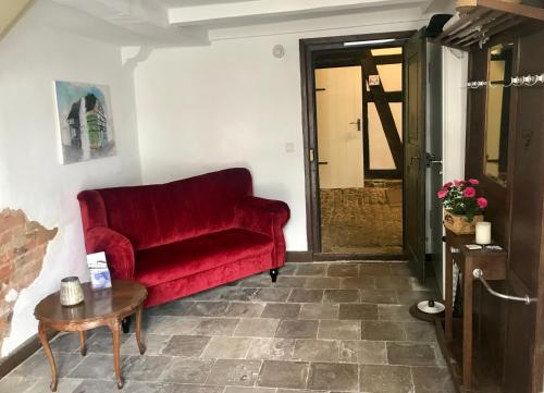 un sofá rojo en una sala de estar con mesa en Haus Buuck - Appartement, en Rüthen