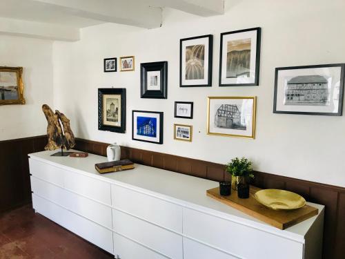 een witte dressoir in een kamer met foto's aan de muur bij Haus Buuck - Appartement in Rüthen