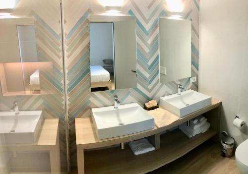 Baño con 2 lavabos y espejo en Hotel President, en Cattolica
