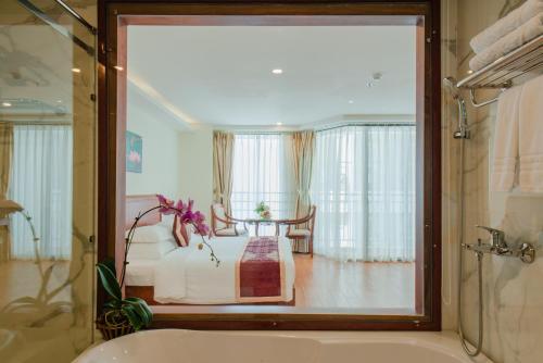 a bathroom with a tub and a room with a table at Red Sun Nha Trang Hotel in Nha Trang
