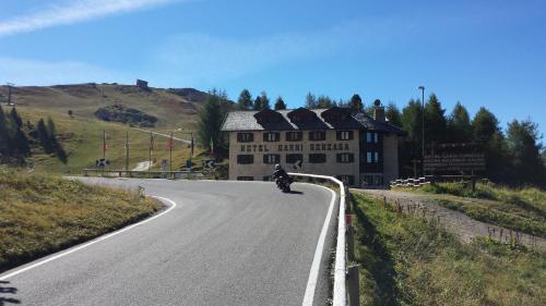 a man riding a motorcycle down a road in front of a building at Hotel Garni Gonzaga in Canazei