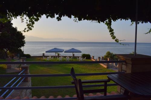 Blick auf das Meer von einem Resort mit Tischen und Sonnenschirmen in der Unterkunft Alexandros Apartments & Αλέξανδρος Villas in Kalamaki Messinia