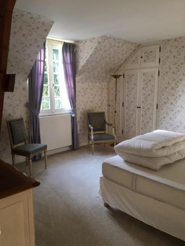 ein Schlafzimmer mit einem Bett und zwei Stühlen und einem Fenster in der Unterkunft L'Hermitage in Saint-Martin-des-Champs