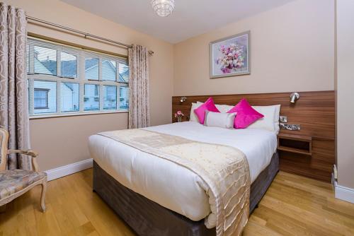 a bedroom with a large bed with pink pillows at Henry Court Townhouse in Kenmare
