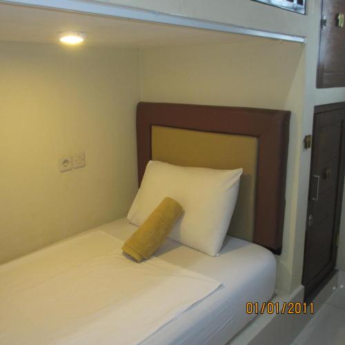 a small bed with a wooden headboard and white pillows at Pondok Aldi Hostel in Amed