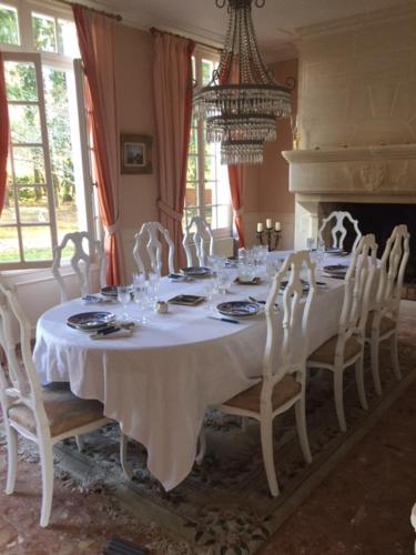 una sala da pranzo con tavolo, sedie e lampadario pendente di L'Hermitage a Saint-Martin-des-Champs