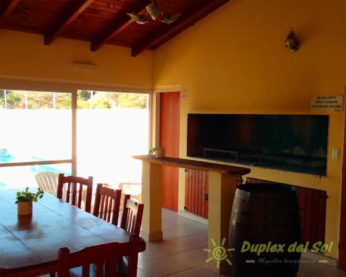 a dining room with a table and a flat screen tv at Duplex del Sol in Villa Carlos Paz