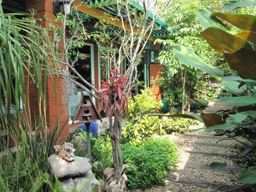 a garden with a bird house next to a building at P.Y. Guest House in Kanchanaburi
