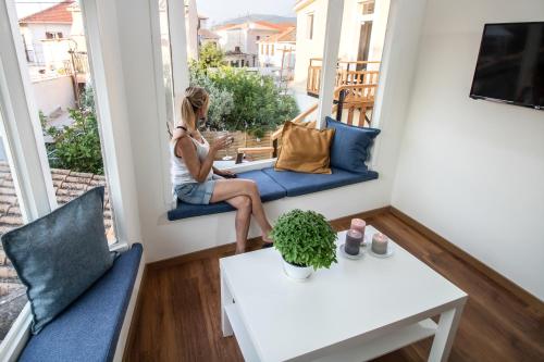 a woman sitting on a blue couch in a balcony at Levkosh Apartments at Lefkada's Heart in Lefkada Town