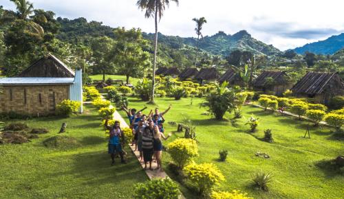 a group of people walking down a path through a village at Namosi Eco Retreat in Navunikambi