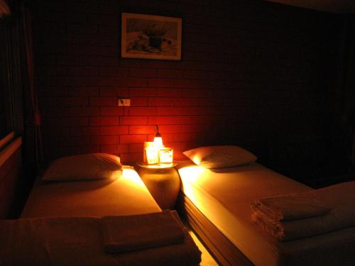 two beds in a dark room with a lit candle at P.Y. Guest House in Kanchanaburi